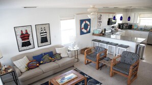 Un salon comprenant un canapé, des fauteuils, une table basse et un tapis sur le thème de la marine.