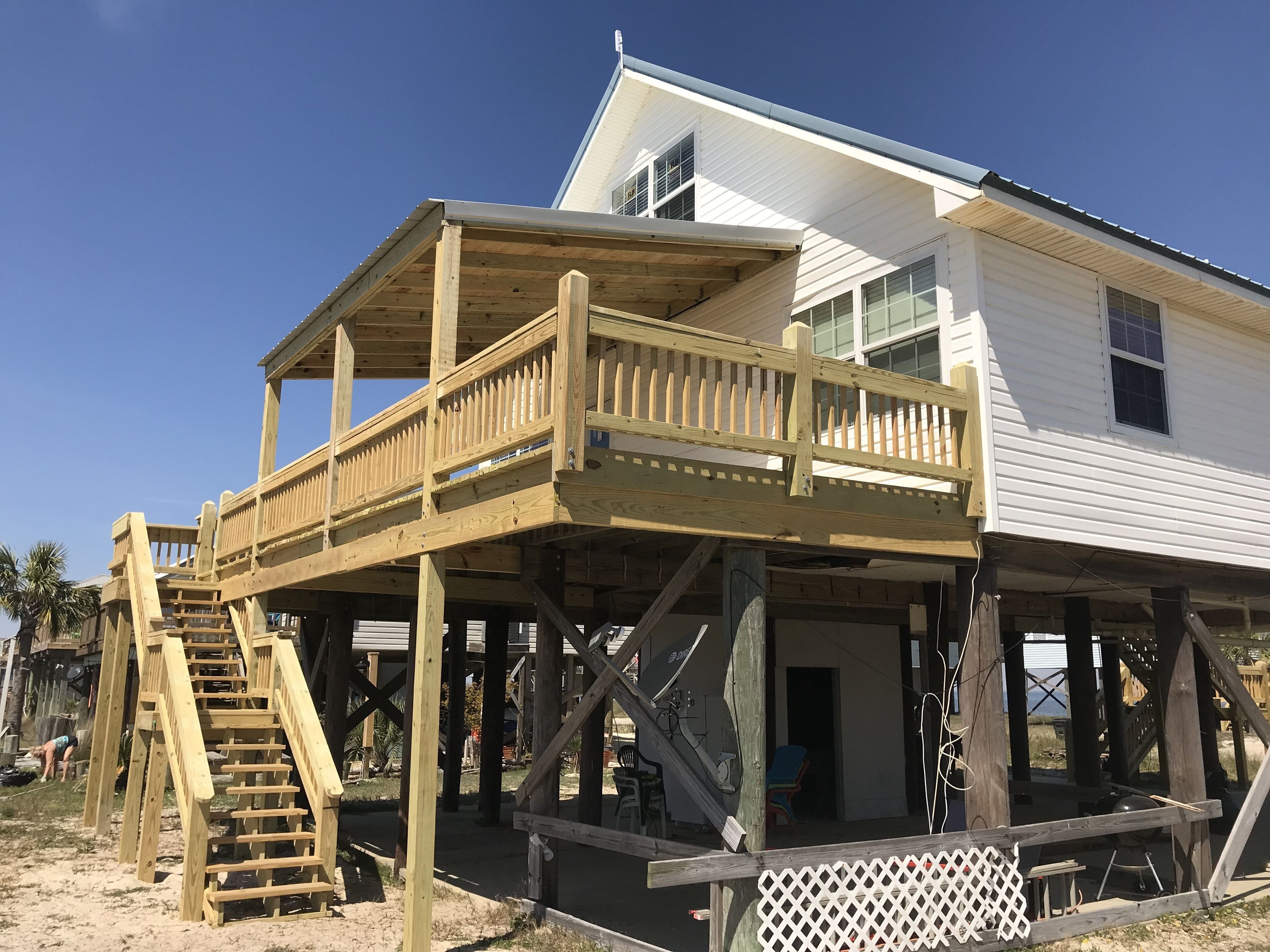 A two-story wooden structure with a balcony, a staircase, and a covered area.