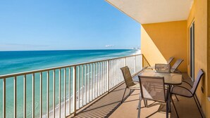 Een balkon met uitzicht op zee, een tafel met stoelen en een hekwerk.