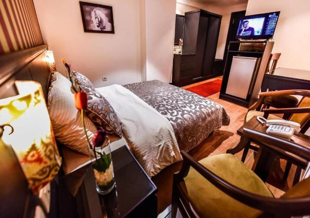 Habitación de hotel con cama, escritorio con teléfono, televisor y armario.