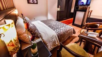 Habitación de hotel con cama, escritorio con teléfono, televisor y armario.