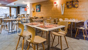 A restaurant with wooden walls, multiple tables, and chairs.