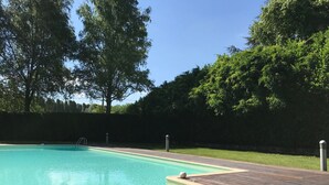 A swimming pool with a wooden deck, surrounded by trees and a hedge. - Historic residence La Quassa Ispra Lake Maggiore (Ispra)