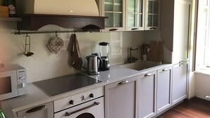 A kitchen with white cabinets, a stainless steel stove, a kettle, and a blender. - Historic residence La Quassa Ispra Lake Maggiore (Ispra)