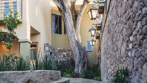 A narrow alleyway with a stone wall, a tree, and a building with a balcony. - Hotel Casa Naré - Adults Only (San Miguel de Allende)