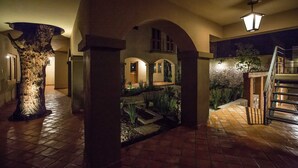 A spacious interior with a central column, arches, a staircase, and a stone wall. - Hotel Casa Naré - Adults Only (San Miguel de Allende)