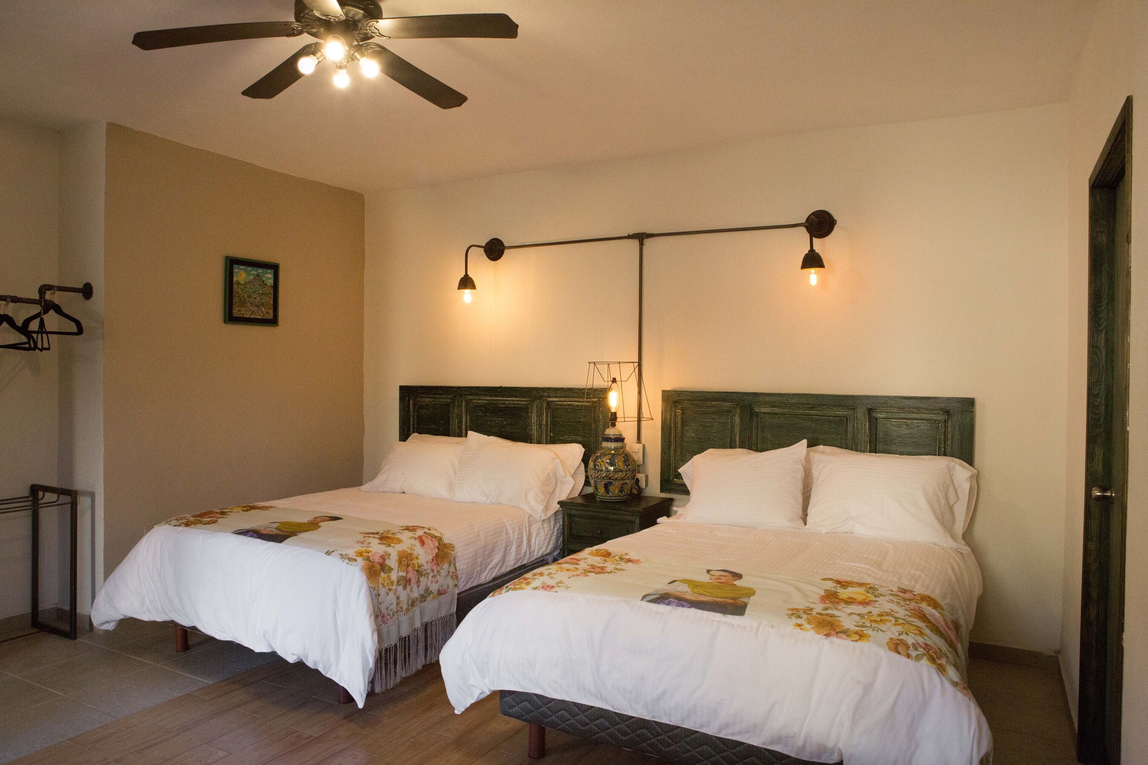 A bedroom with two beds, a ceiling fan, and bedside lamps.