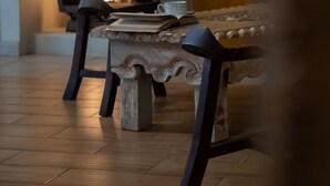 A dining area with a table and chairs, a decorative lamp, and a fireplace with a visible fire. - Hotel Casa Naré - Adults Only (San Miguel de Allende)