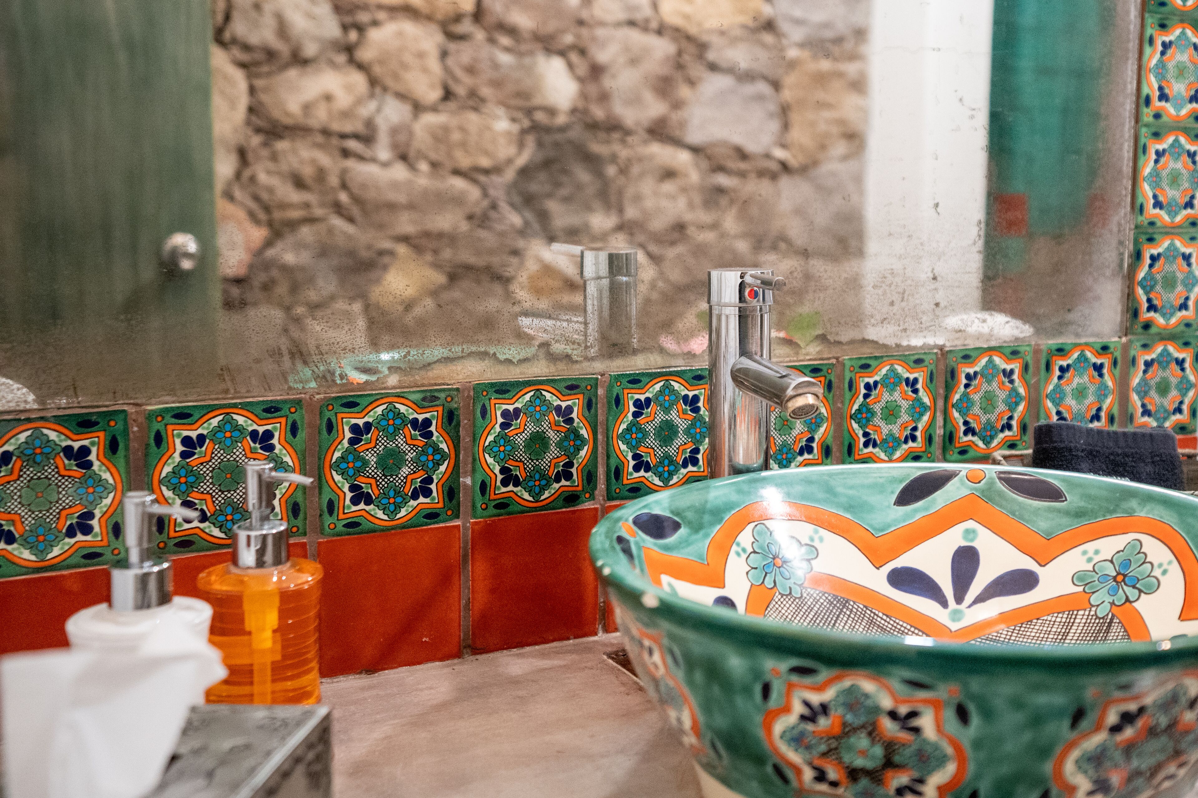 A bathroom with a decorative sink, a soap dispenser, and a towel rack.