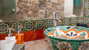 A bathroom with a decorative sink, a soap dispenser, and a towel rack.