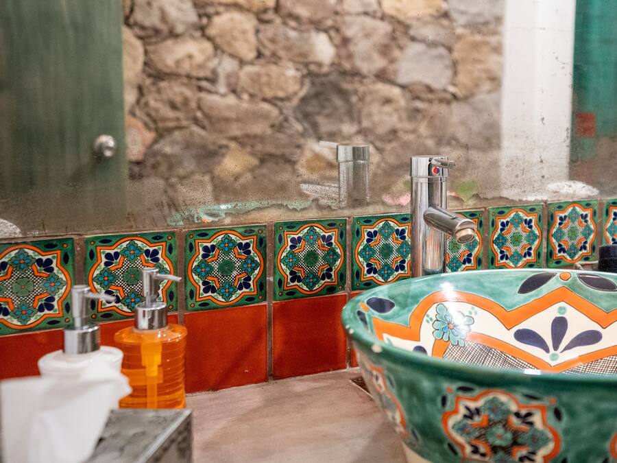 A bathroom with a decorative sink, a soap dispenser, and a towel rack.