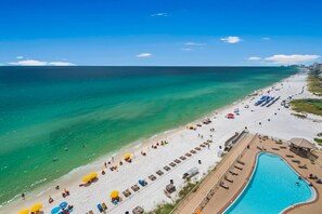 Un complexe hôtelier de bord de mer doté d’une piscine, de chaises longues et de parasols.