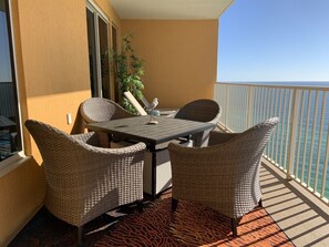 Een balkon met rieten meubels, een tafel en uitzicht op zee.