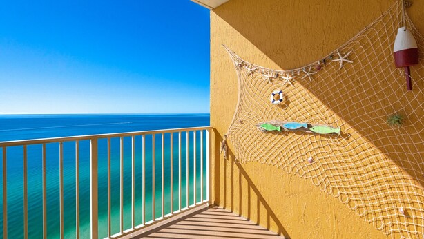 Un balcón con vista al océano, una red con estrellas de mar y juguetes de peces, y un flotador.