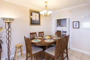 A dining room with a round table, six chairs, and a chandelier.