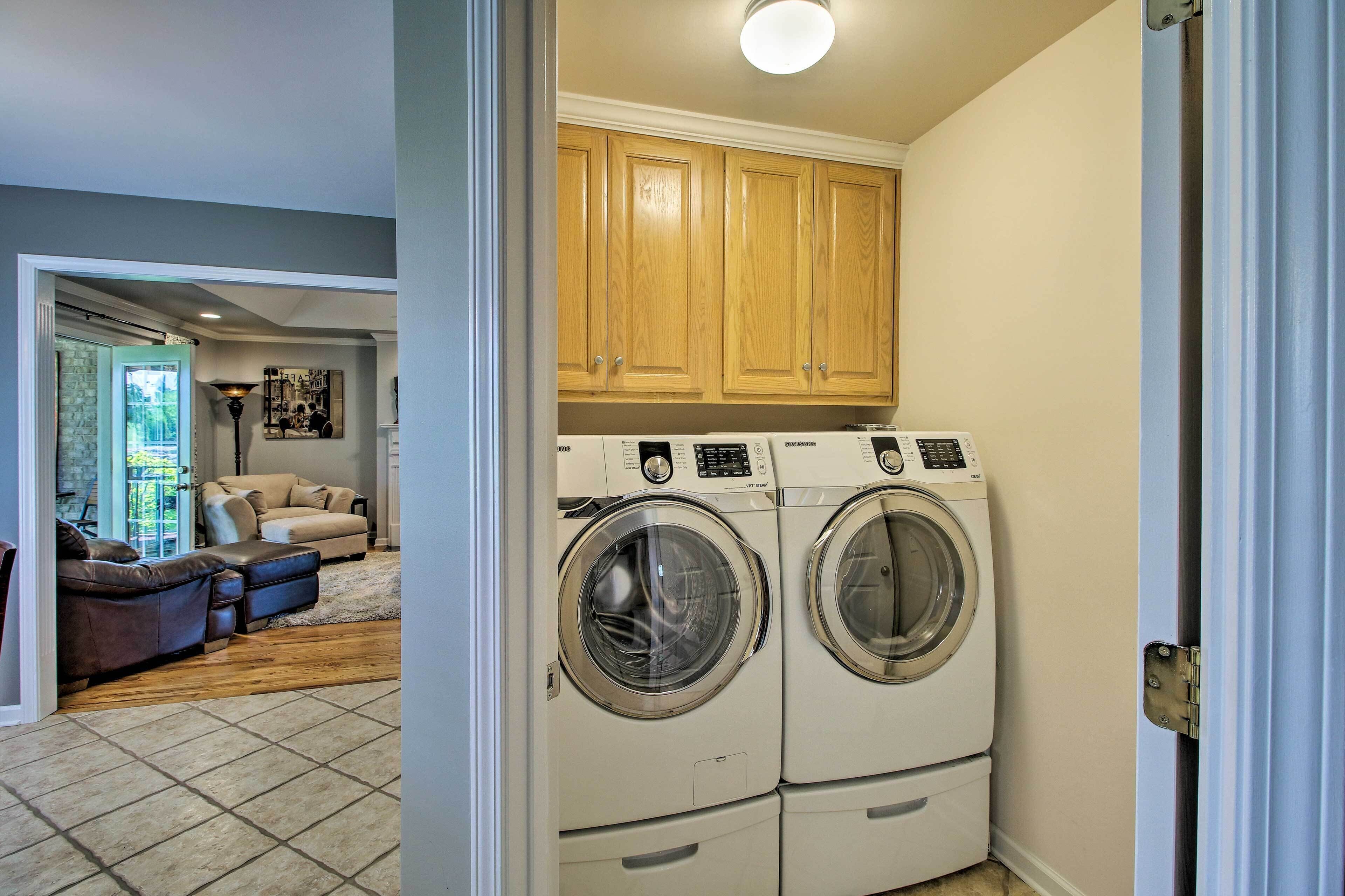A laundry room with two front-loading washing machines and wooden cabinets above.