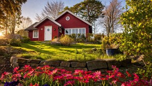 Une maison rouge avec une pelouse bien entretenue et une bordure en pierre.