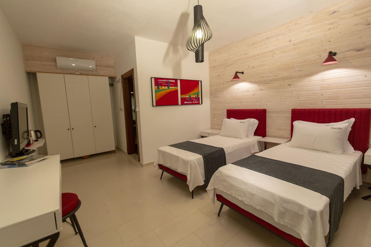 Ein Hotelzimmer mit zwei Betten, einem Schreibtisch, einem Stuhl und einem Fernseher.