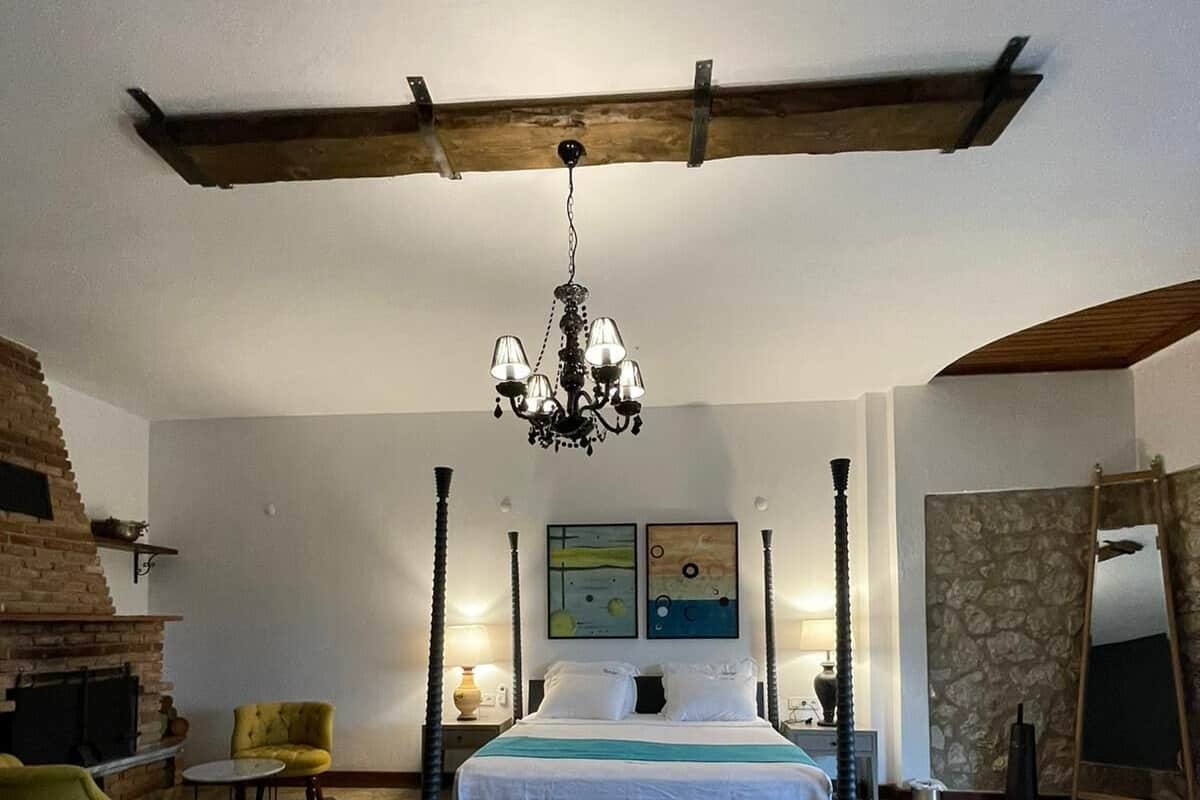 Ein Schlafzimmer mit Steinboden, einem Himmelbett, einer Chandelüster, einem Kamin und Kunstwerken an den Wänden.