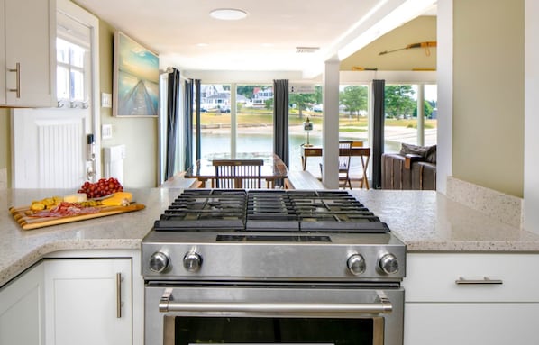 Una cocina con estufa a gas, horno y comedor con vista a un cuerpo de agua.