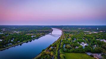 An aerial view of a river with a bridge, surrounded by greenery and residential areas.