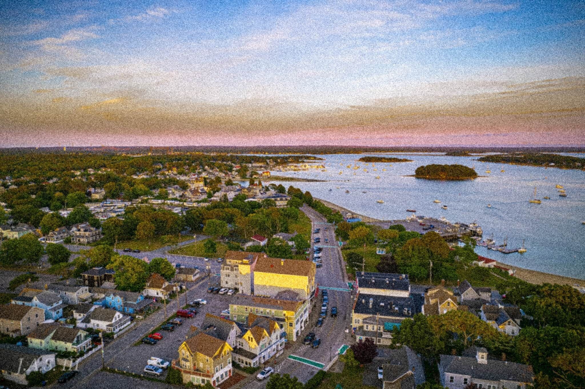 An aerial view of a coastal town with buildings, roads, and boats.