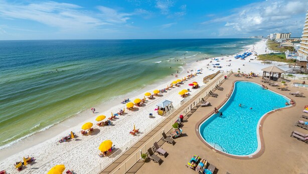 Ein Strandresort mit Schwimmbad, Strandliegen und einer Promenade.