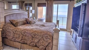 A spacious bedroom with a large bed, a ceiling fan, and a view of the ocean.