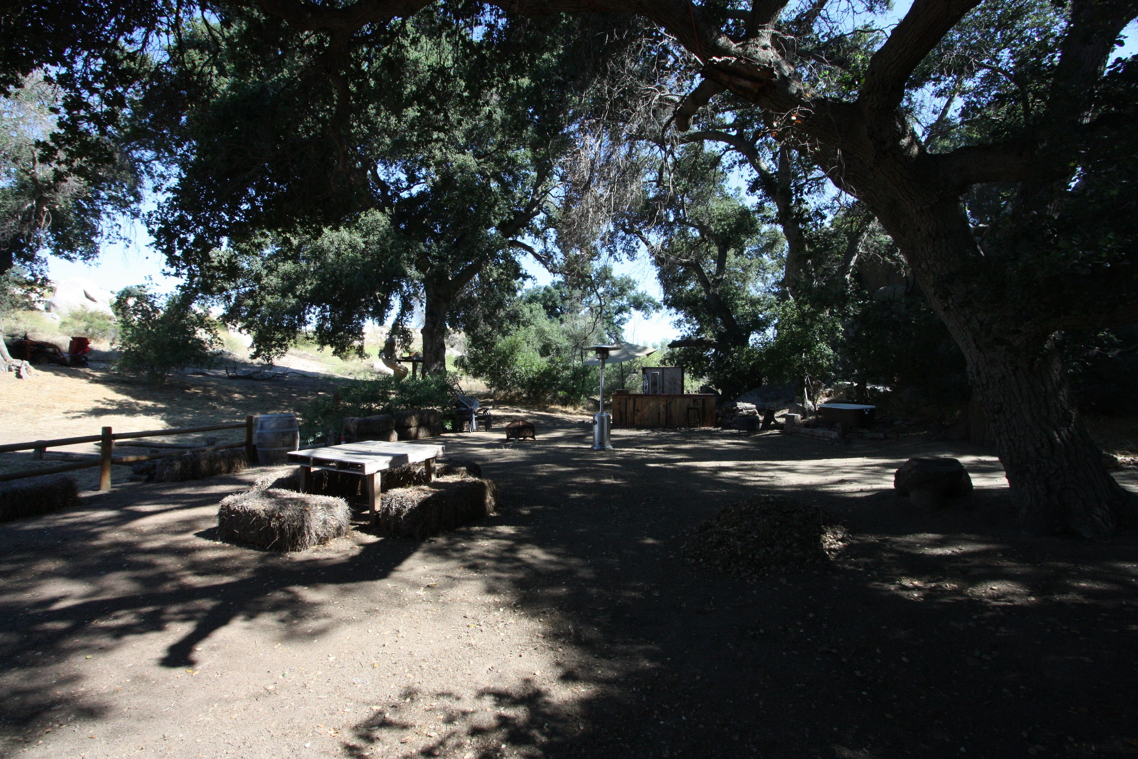 A campsite with picnic tables, hay bales, and a wooden fence.
