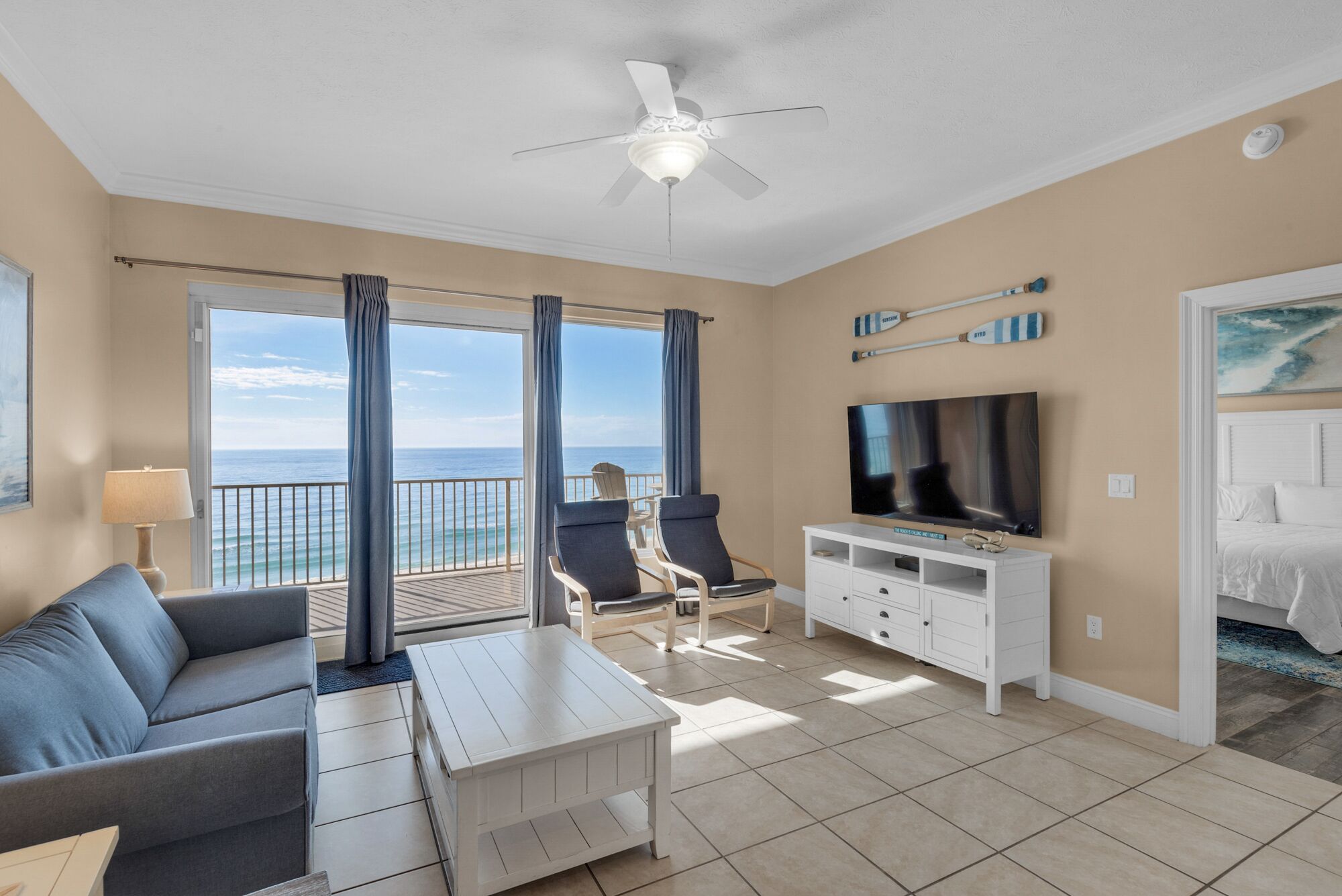 Quarto de hotel com varanda, televisão, sofá e mesa de jantar.