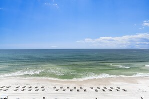 A beach with rows of sun loungers and a clear view of the ocean.