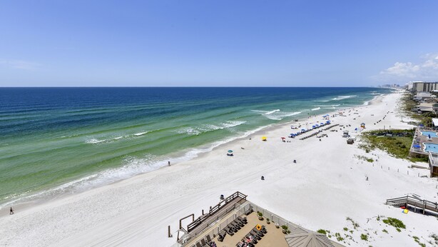 Een strandresort met een lang zandstrand, een zwembad en uitzicht op de oceaan.