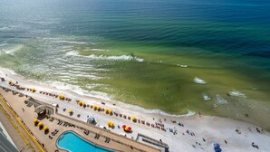 Een strand met een zwembad, ligbedden en parasols.