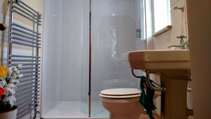 Une salle de bain avec une douche à parois de verre, des toilettes et un lavabo avec un miroir au-dessus.