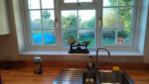 A kitchen with a window, a sink, and a scale on the windowsill. - Private countryside cottage in Herefordshire (Hereford)