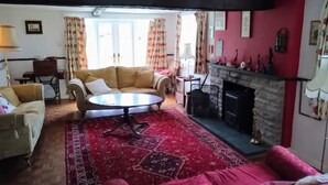 A cozy living room with a fireplace, a round coffee table, and a red carpet. - Private countryside cottage in Herefordshire (Hereford)