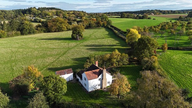 A white house with a red roof surrounded by green fields and trees. - Private countryside cottage in Herefordshire (Hereford)