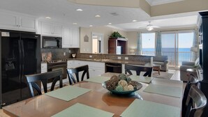 A spacious kitchen with white cabinets, a black refrigerator, and a dining area with a table set for four.