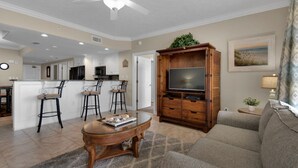 A modern living room with a wooden entertainment center, a glass coffee table, and a gray sofa.