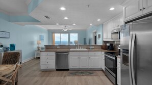 A modern kitchen with white cabinets, stainless steel appliances, and a large island with a sink. - 1107-11th Floor-BEACH CHAIRS & UMBRELLA INCL-Outdoor Pool-AMAZING BEACH  VIEW! (Panama City Beach)
