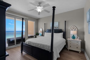 A four-poster bed with a view of the ocean through a sliding glass door.