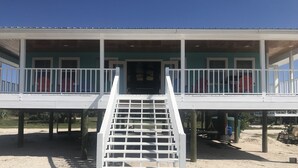 A two-story building with a covered porch and a staircase leading to the upper level.
