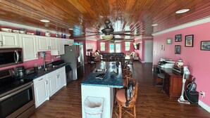 A spacious kitchen with wooden ceiling, a central island, and a dining area with a view.