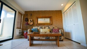 A living room with a sofa, a coffee table, a guitar, and a framed picture on the wall.