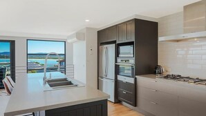 A modern kitchen with a large island, built-in appliances, and a view of the outdoors.