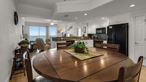 A spacious dining area with a round table, chairs, and a view of the ocean. - 1211-12th Flr-2 Bedrooms-Sleeps 8-Outdoor Pool-Fitness Center-Hot Tub (Panama City Beach)