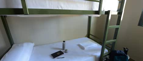 A bunk bed with a white mattress and a metal ladder. A backpack is placed against the wall beside the bed.