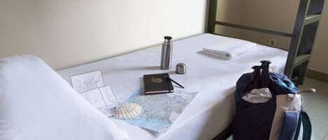A neatly made bed with a map, a journal, a thermos, and a backpack.
