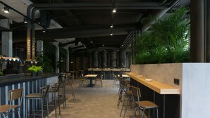 A modern restaurant with high ceilings, exposed ductwork, and a long counter with stools. - Hostel Monte Do Gozo (Santiago de Compostela)