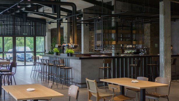 A modern cafe with a bar area, seating arrangements, and a view of the outside. - Hostel Monte Do Gozo (Santiago de Compostela)